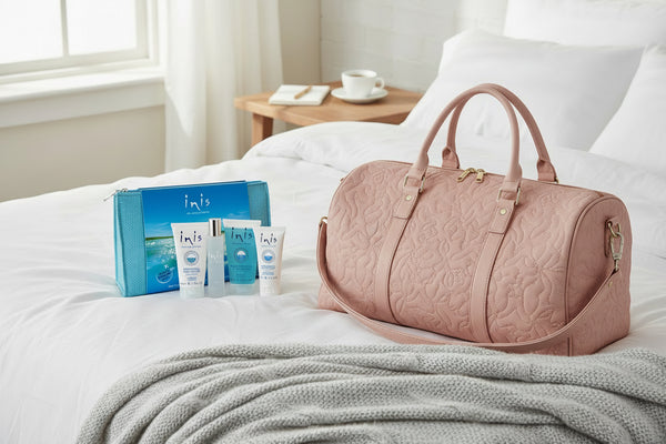 Inis Travel set on a bed by an overnight bag 