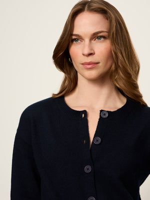 A woman wearing a dark navy blue knit cardigan sweater with a buttoned neckline, shown from the chest up against a plain light background.