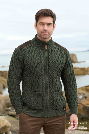 Man wearing a green knitted sweater with brown accents by a coastal background