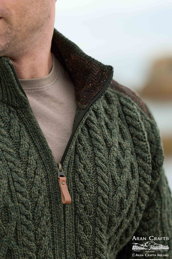 Close-up of a person wearing a green cable knit jacket with a blurred background
