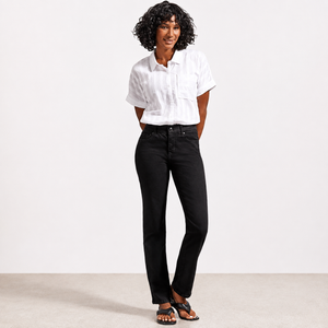 A woman modeling a white short-sleeve button-up shirt and black straight-leg jeans against a clean white studio background.