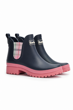 A pair of Barbour rain boots in black with a pink sole and a plaid elastic side panel, shown on a white background.