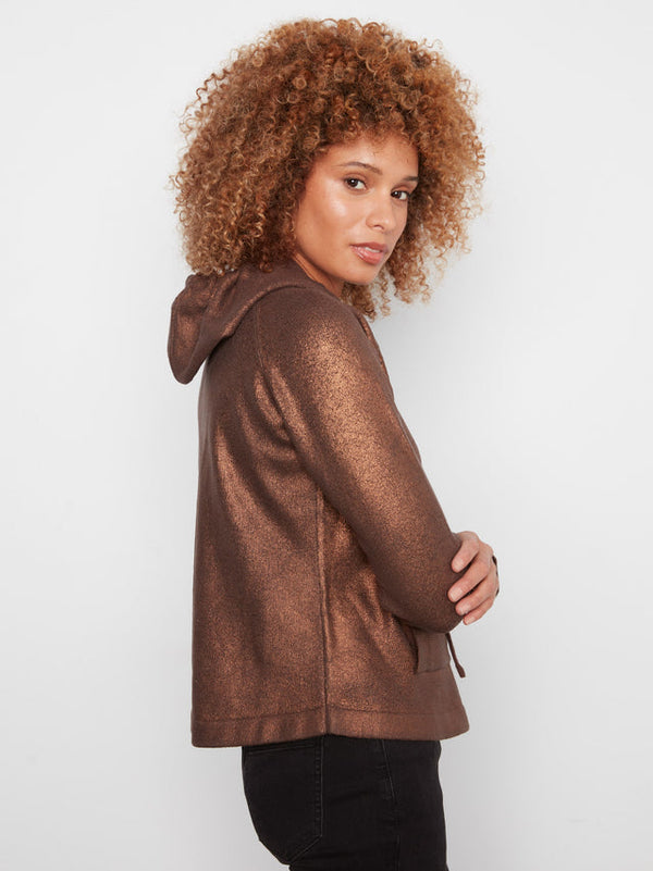 A woman with curly light brown hair wearing a metallic bronze-brown hooded sweatshirt, shown from a side-back angle against a plain light gray studio background.