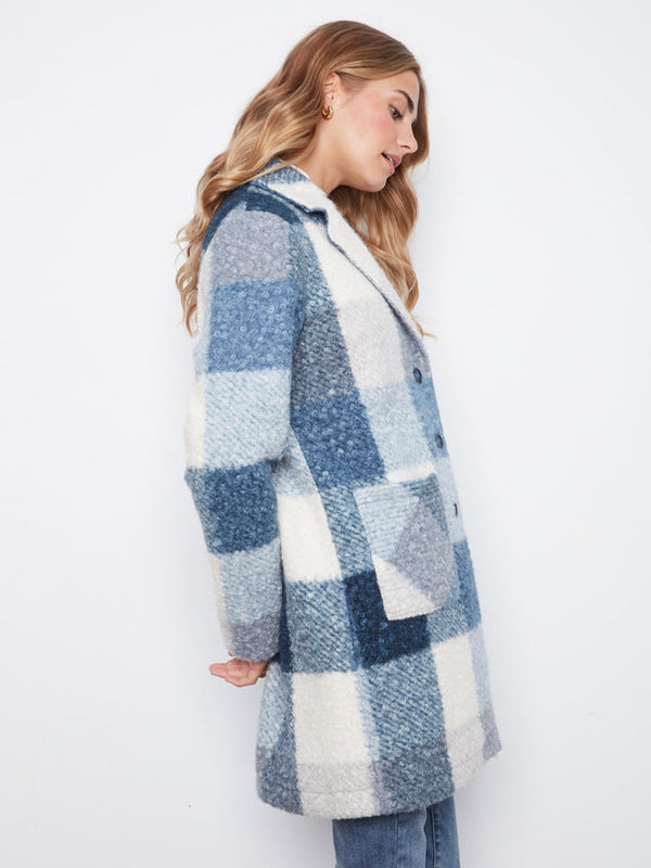 A woman wearing a blue and white checkered fuzzy coat, shown from a side profile against a plain white background.