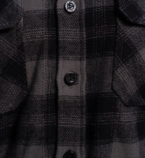 Close-up of a black and gray plaid shirt with buttons.
