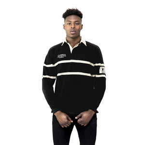 Person wearing a black and white striped rugby shirt with a visible brand logo on a white background