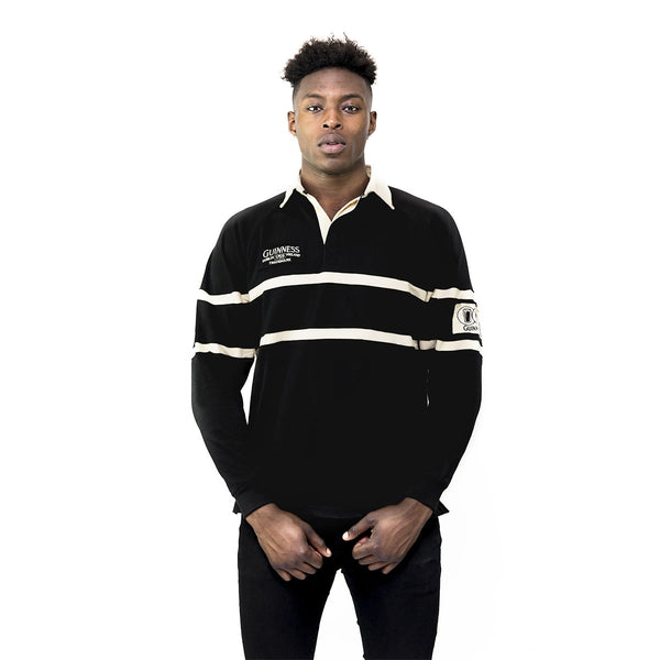 Person wearing a black and white striped rugby shirt with a visible brand logo on a white background