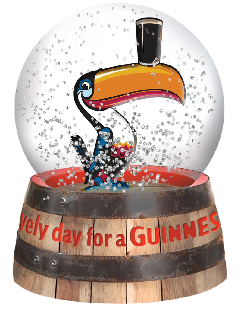 Snow globe with a toucan character and 'Every day for a Guiness' text on a wooden barrel base.