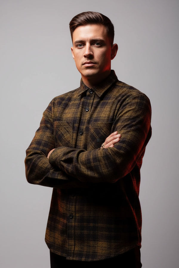 Man wearing a plaid shirt and cap against a dark background