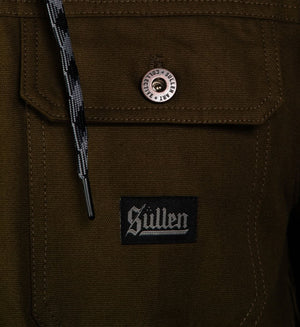 Close-up of a brown jacket with a button and 'Sullen' logo patch.
