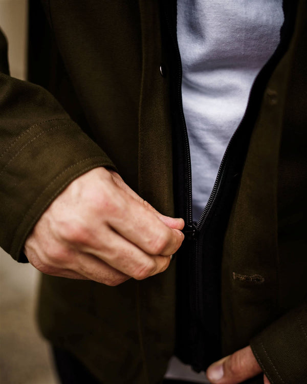 Person zipping up a dark jacket with a light shirt underneath