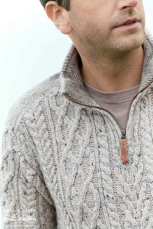 Man wearing a cable knit sweater with a zipper on a white background