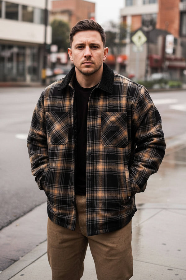 Person wearing a plaid shirt with a blurred urban background